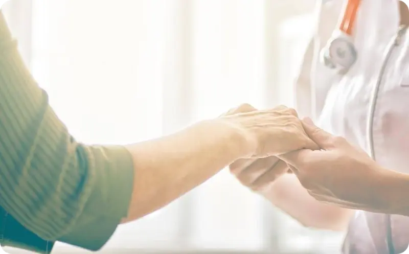 Arts houdt handen vast van patiënt.